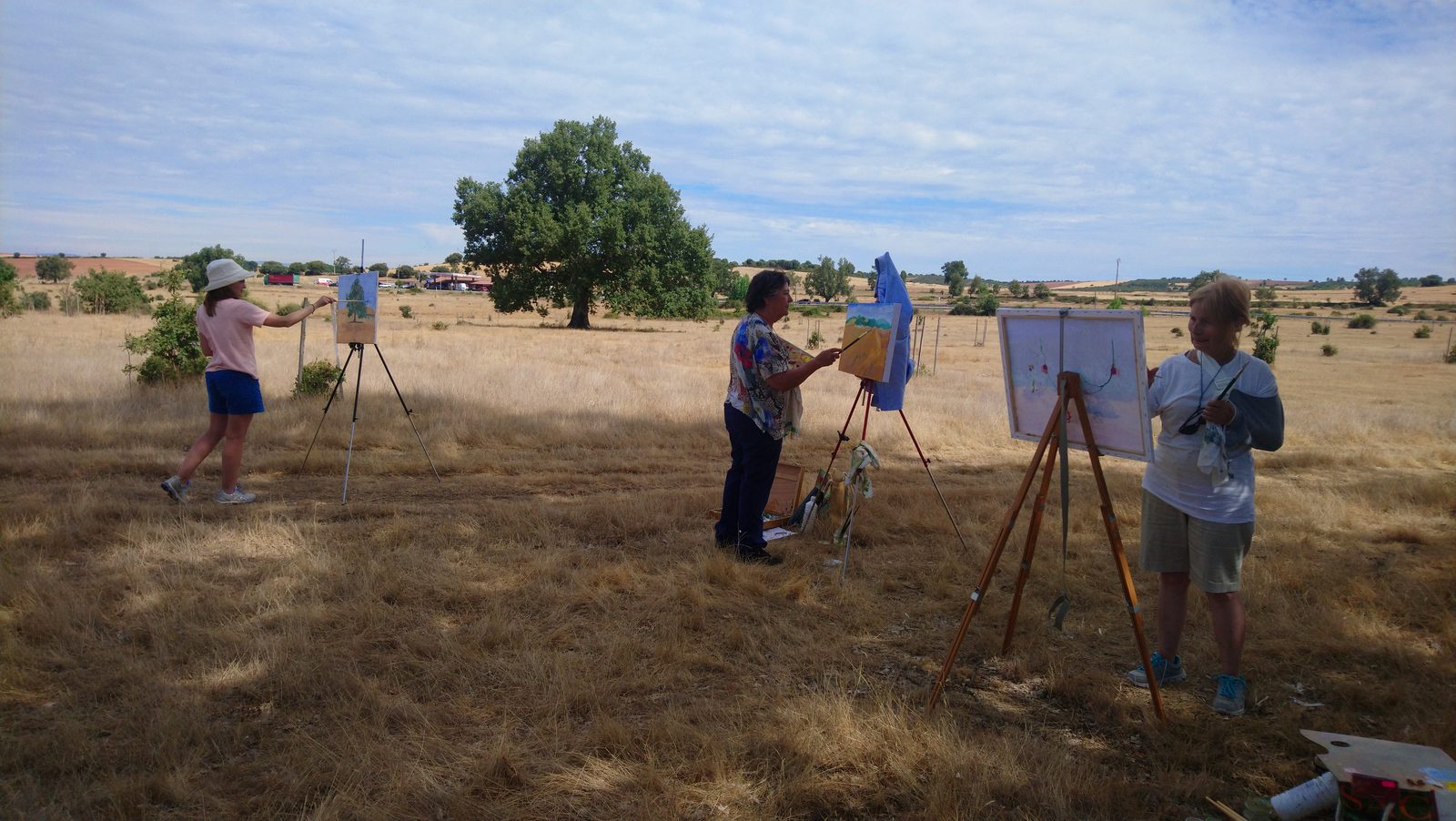 Tres participantes pintando al aire libre en la campiña alistana