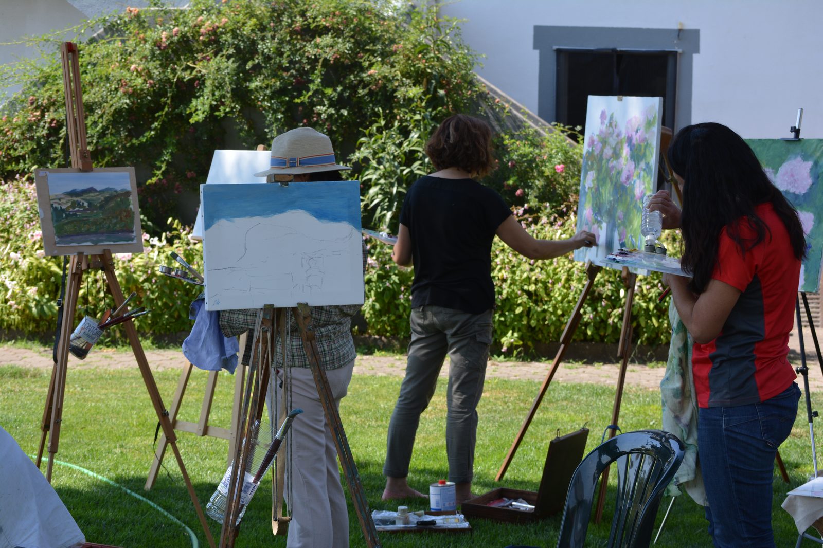 Tres participantes pintando junto a una casa de Sejas