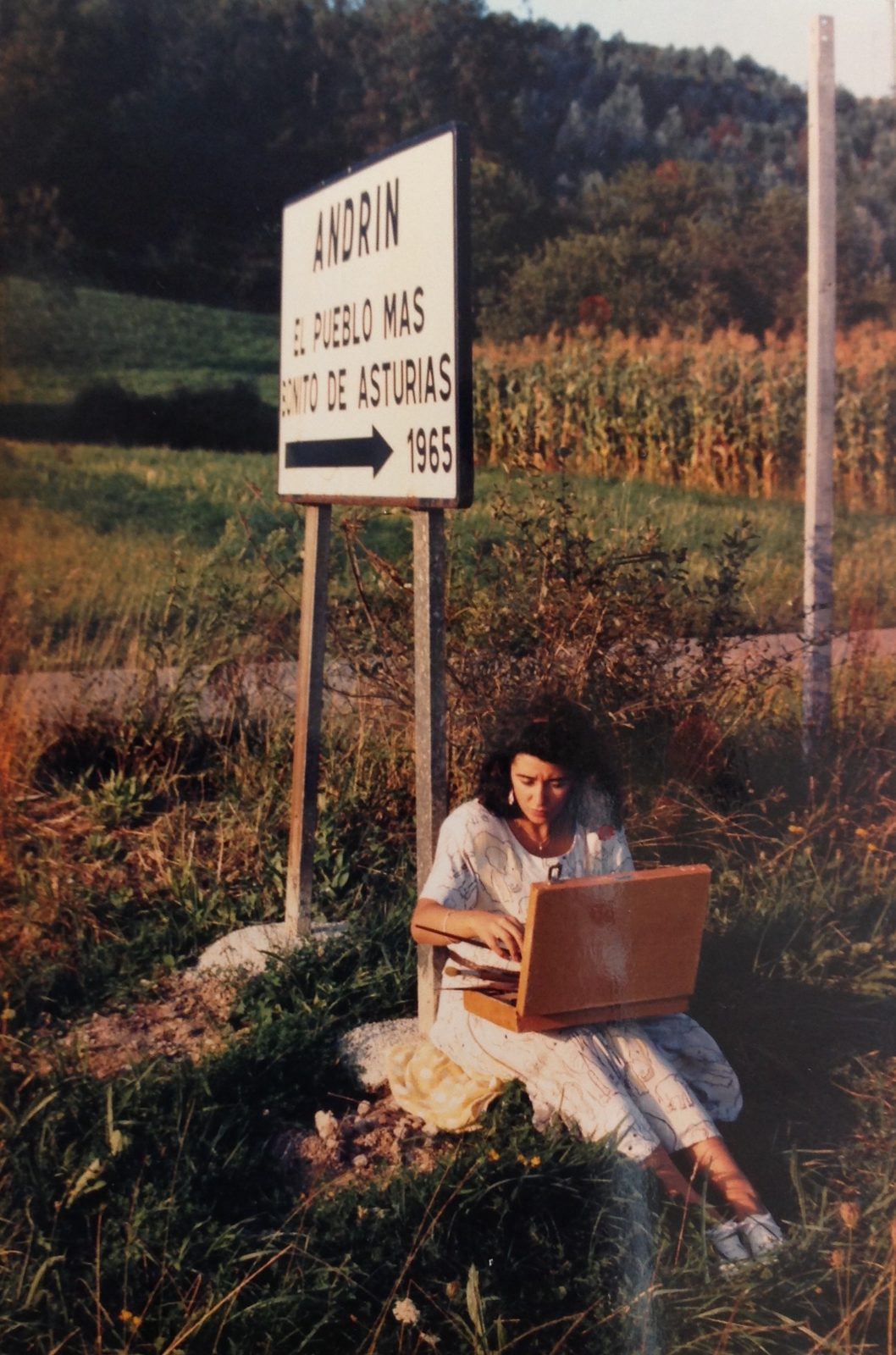 Gloria pintando junto al cartel de Andrín, Asturias, en los años noventa